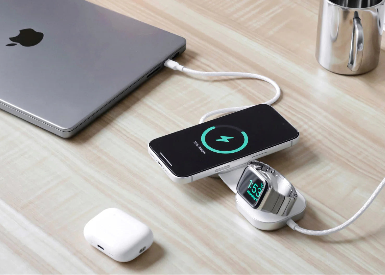 MacBook charging cable connected to devices charging an iPhone and smartwatch on a home office desk