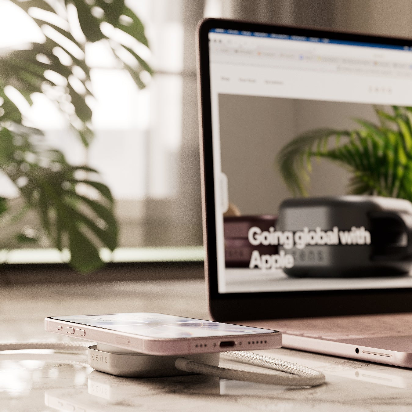 Wireless charging cable connected to a MacBook Neo charging an iPhone on a desk