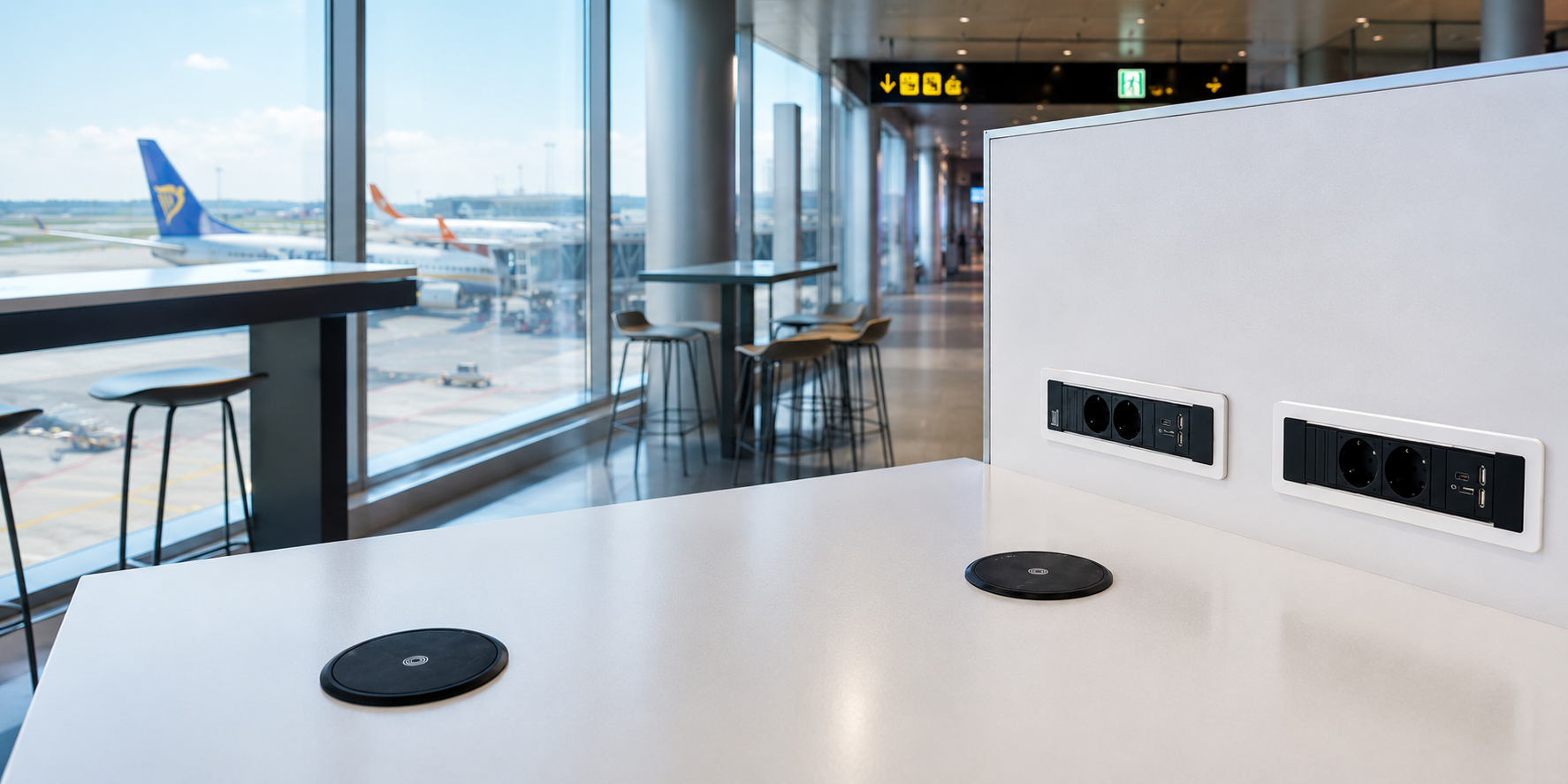 Built in wireless chargers integrated into a table at an airport charging smartphones.