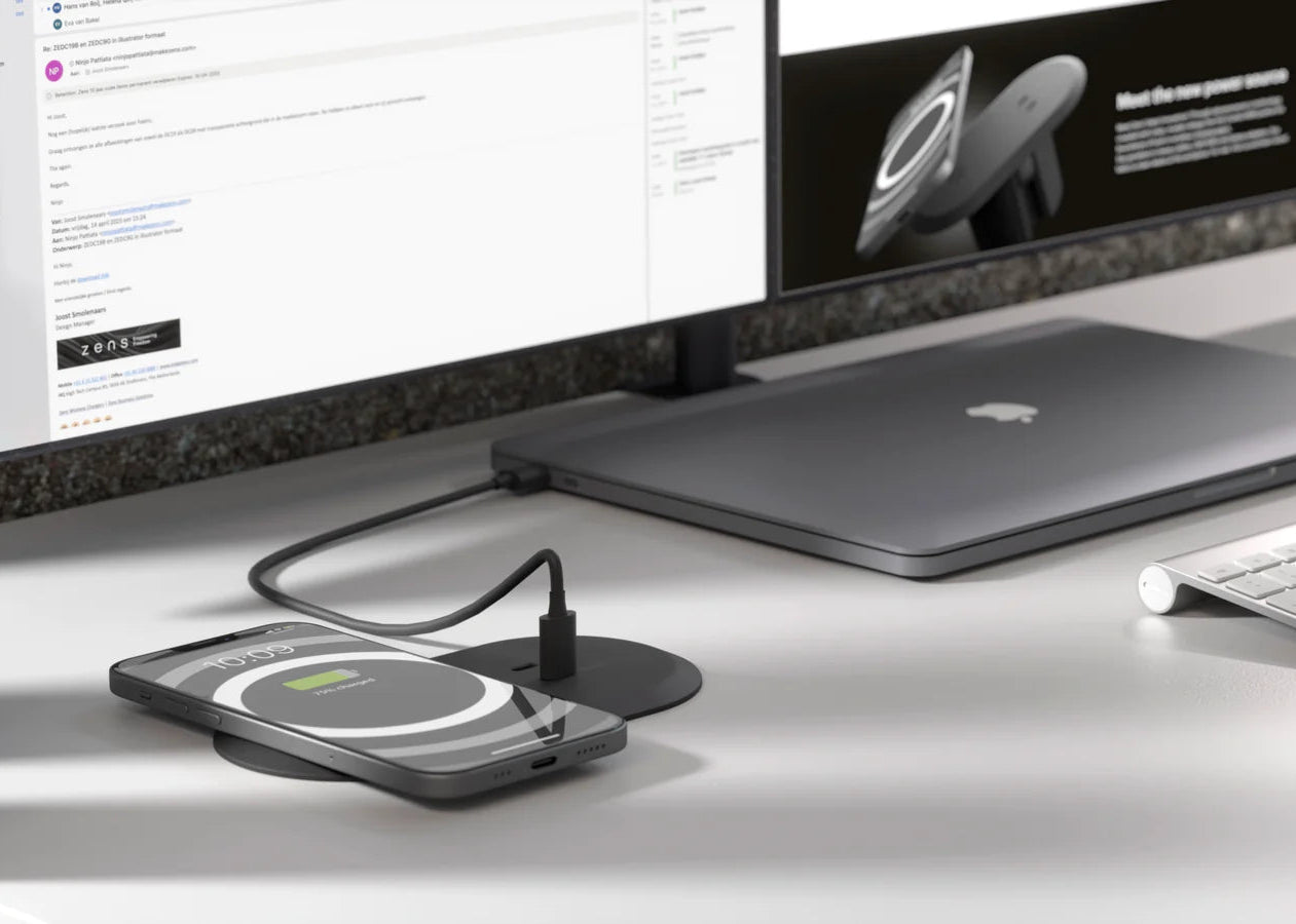 Built in desk power outlet with HDMI port and wireless charging pad charging an iPhone and MacBook simultaneously in an office workspace