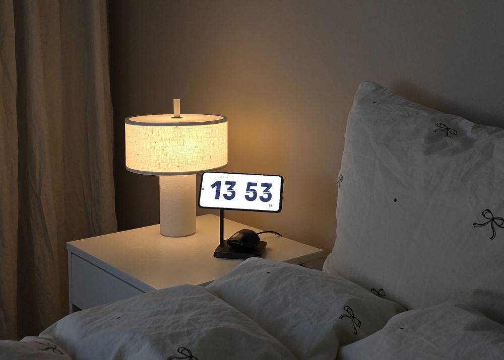 Magnetic wireless charger charging a Samsung smartphone on a bedroom nightstand.