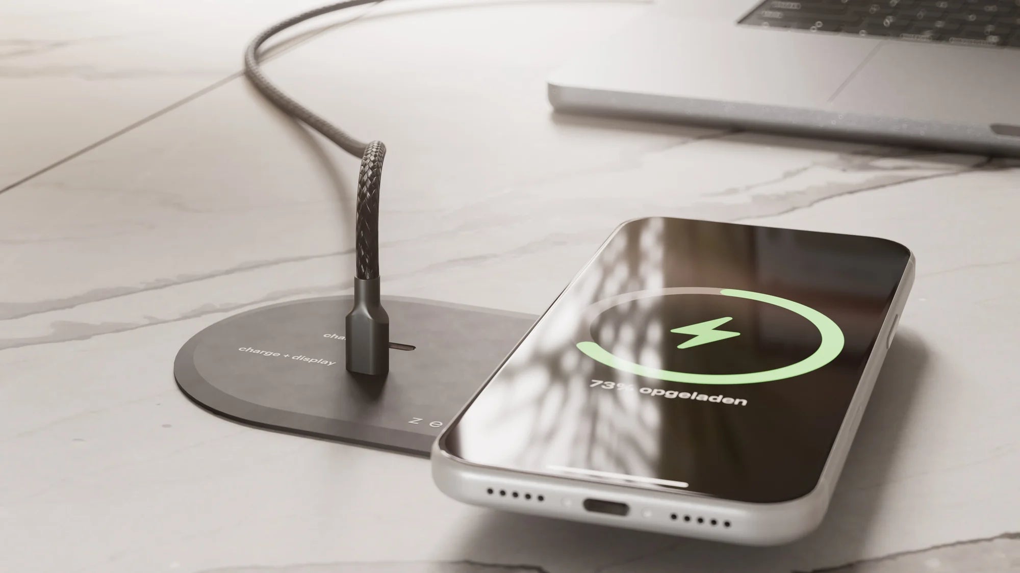 iPhone charging on a built in wireless charger while an HDMI cable connects a laptop to an external display and charges it in a workspace