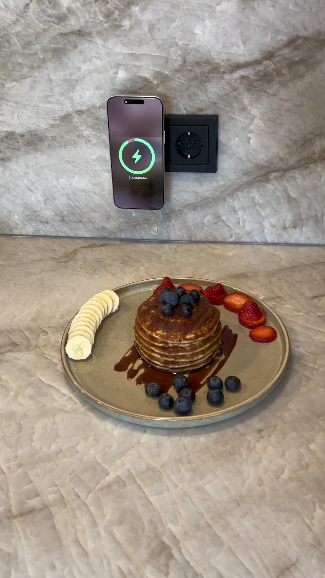 Smartphone charging wirelessly on a adapter placed on a kitchen counter for a recipe