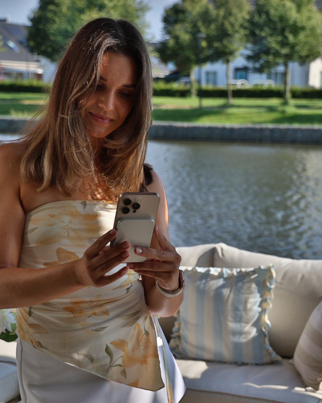 White MagSafe power bank attached to and charging a smartphone in a lifestyle setting.