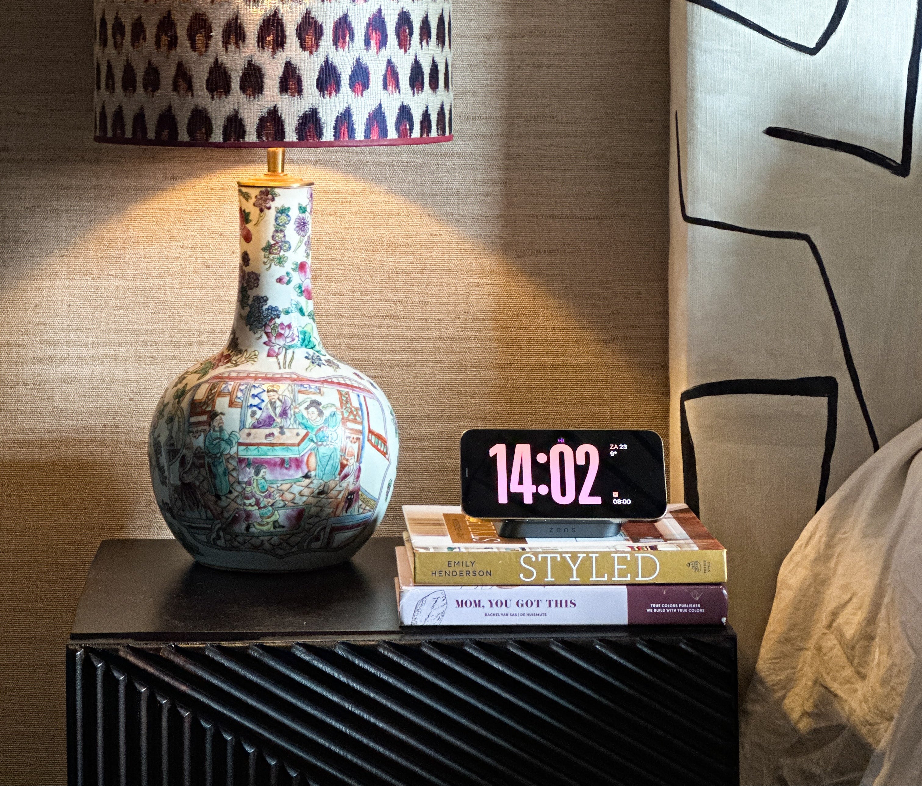 Magnetic nightstand charger wirelessly charging a smartphone on a nightstand next to a bed.