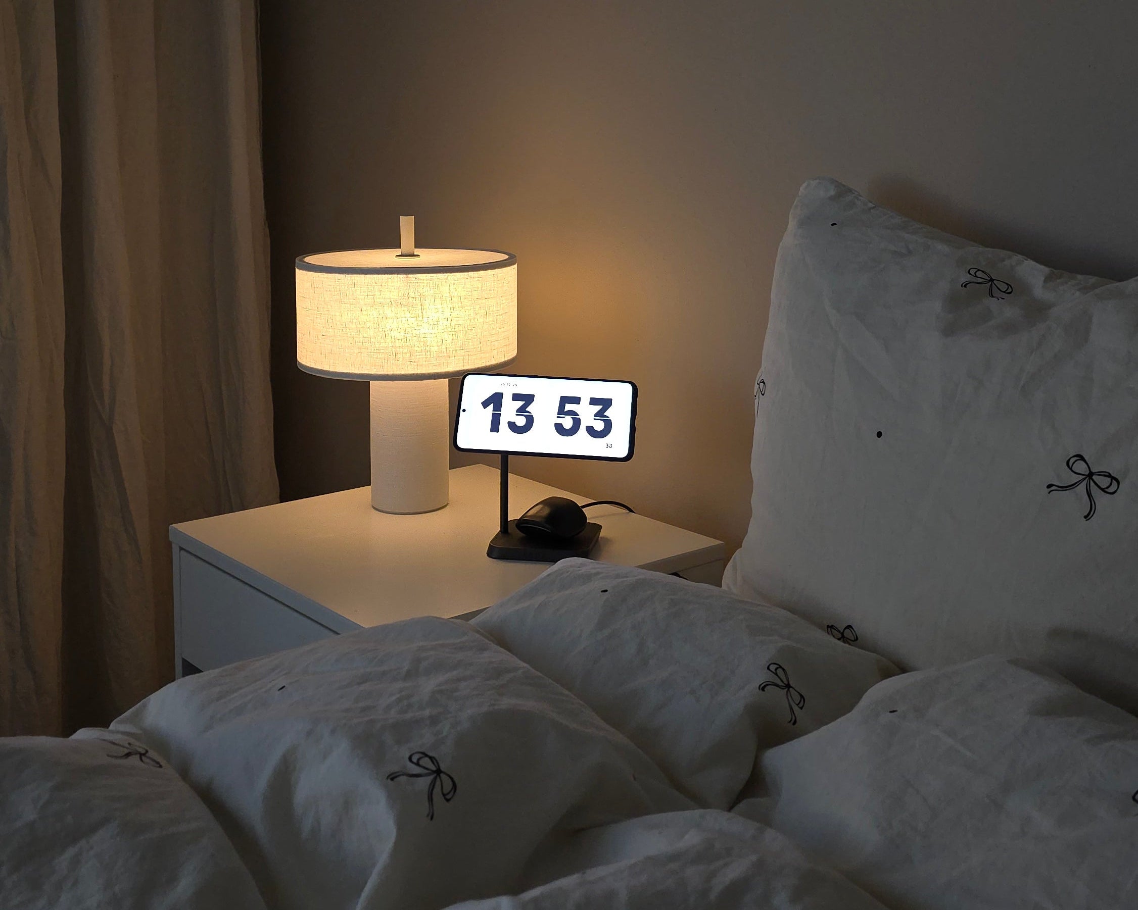 Zens magnetic 2 in 1 wireless charger charging a Samsung phone displaying a clock and wireless earphones on a bedroom nightstand
