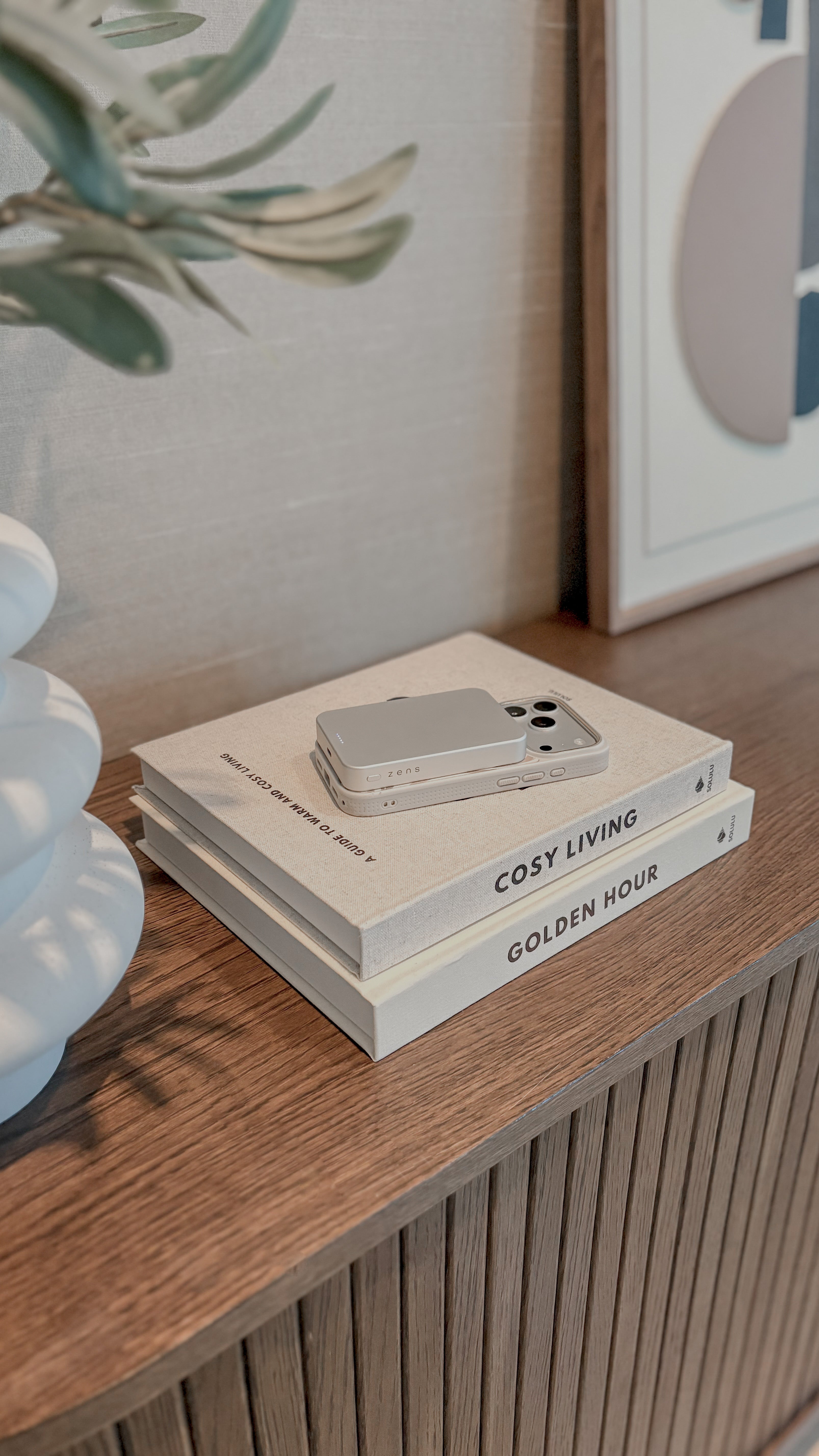 White MagSafe power bank attached to and charging a smartphone in a lifestyle setting.