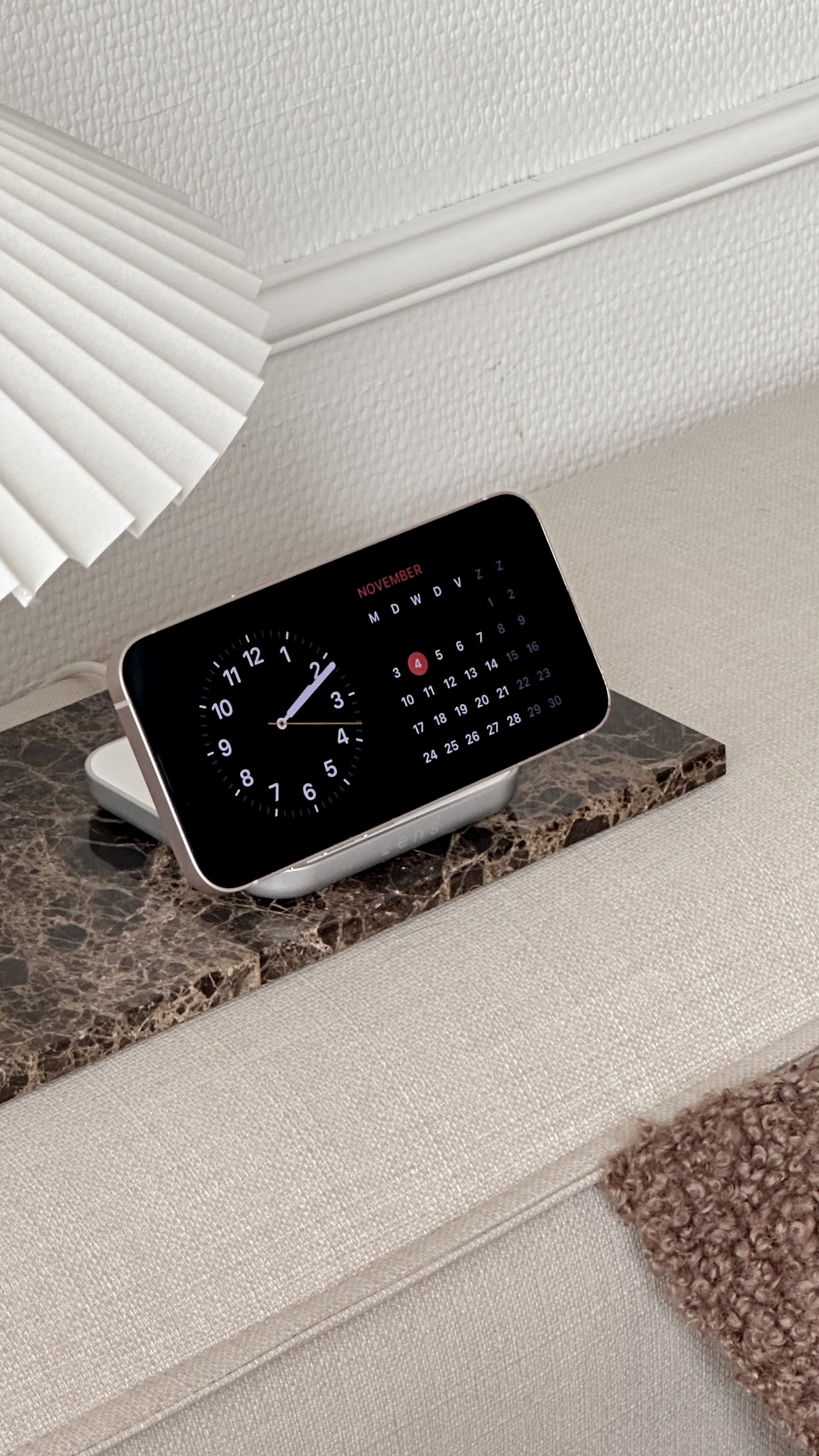Zens Magnetic Nightstand Charger wirelessly and magnetically charging a smartphone in a lifestyle setting.