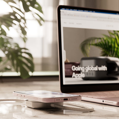 Wireless charging cable connected to a MacBook Neo charging an iPhone on a desk