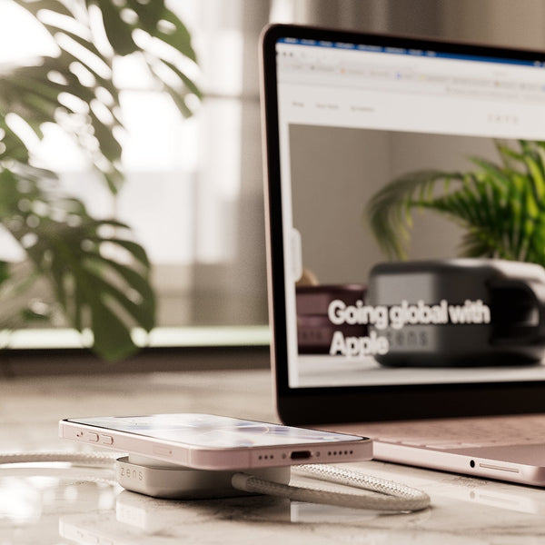 Wireless charging cable connected to a MacBook Neo charging an iPhone on a desk