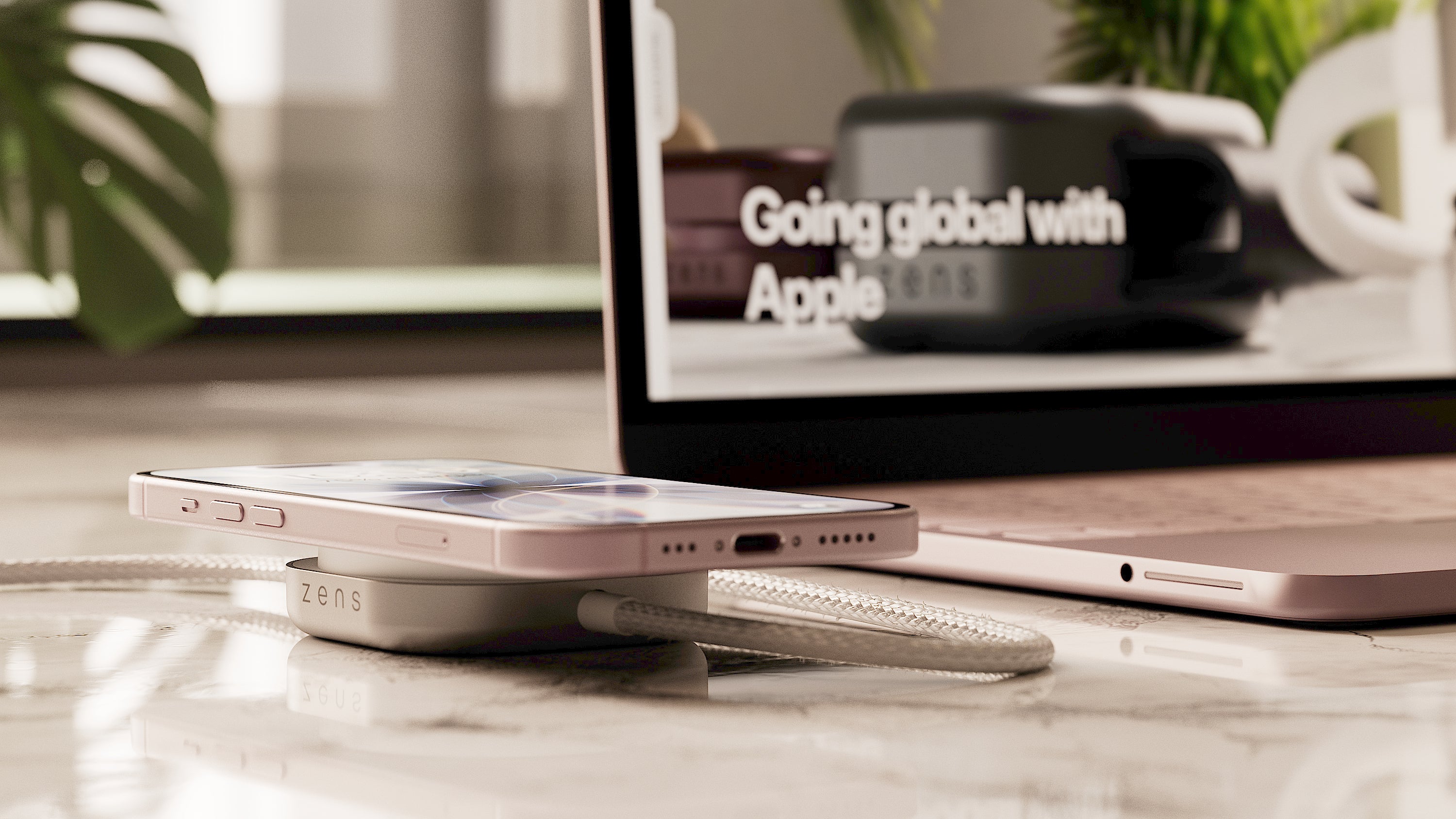 Wireless charging cable connected to a MacBook Neo charging an iPhone on a desk