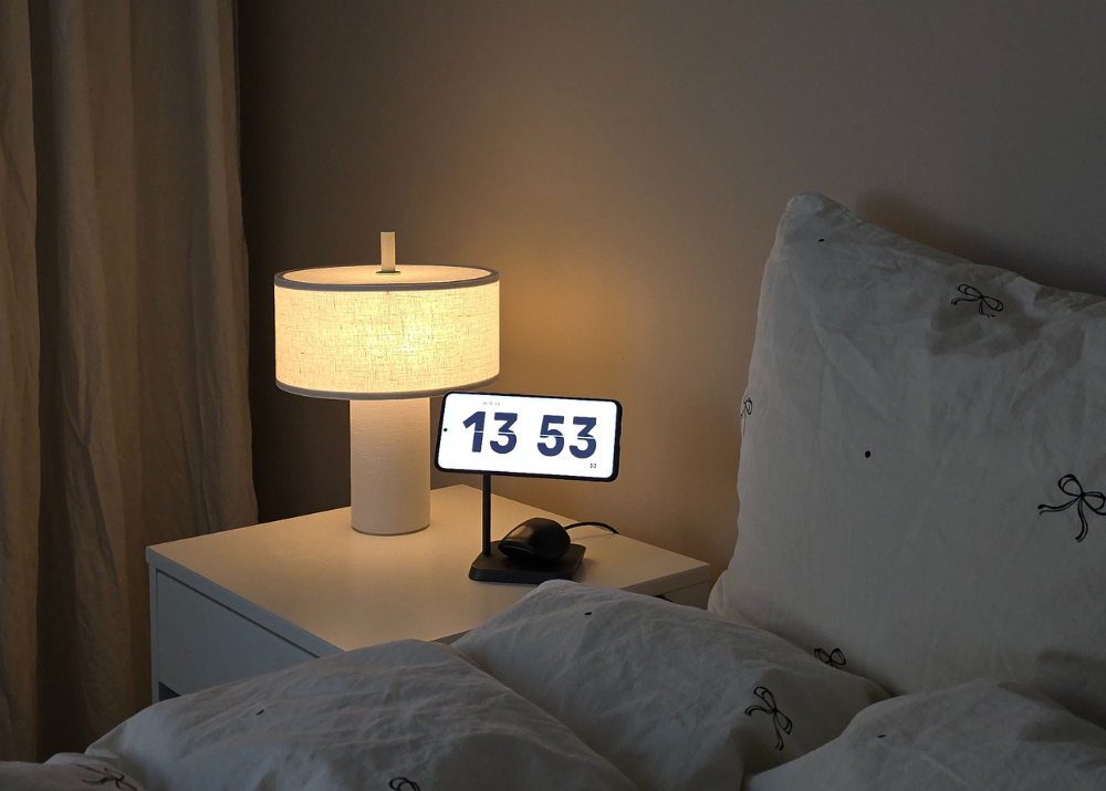 Zens 2 in 1 wireless charger charging a Samsung smartphone and Samsung earbuds on a bedside table in a bedroom