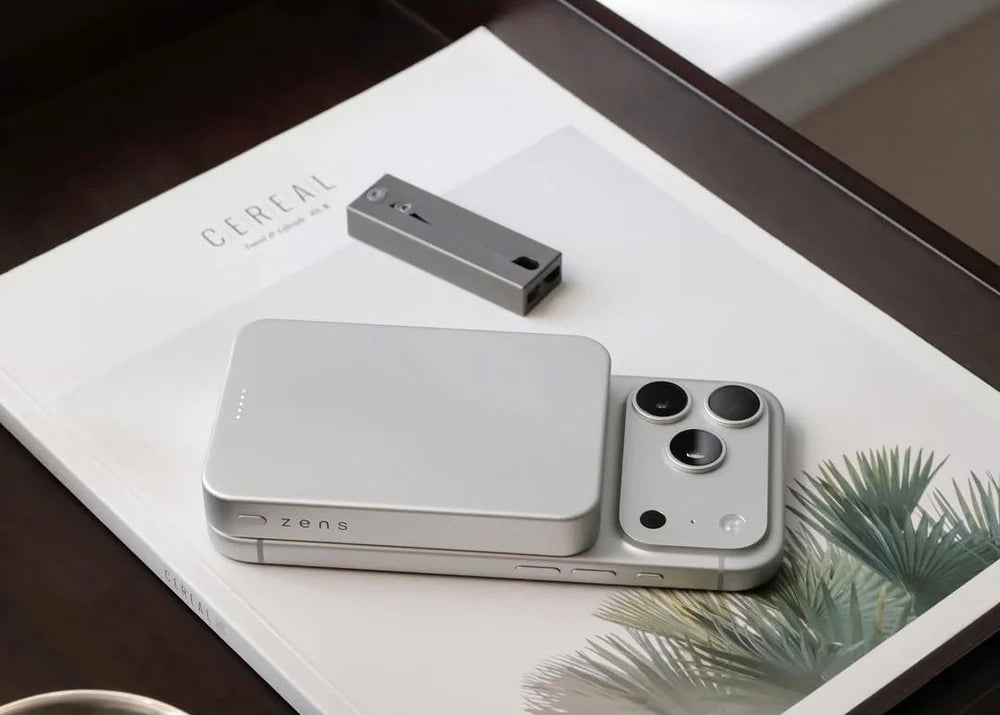 iPhone wirelessly charging with a Zens MagSafe powerbank on a coffee table at home
